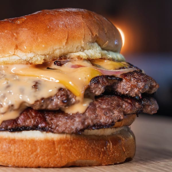 A Holy Buckets double smash burger with melted cheese and sauce on a toasted bun.
