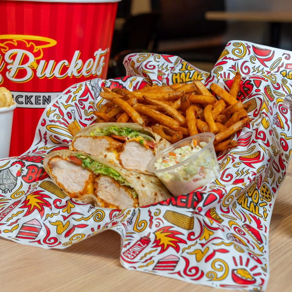Holy Buckets Halal Chicken wrap with fries and coleslaw in a branded paper basket.