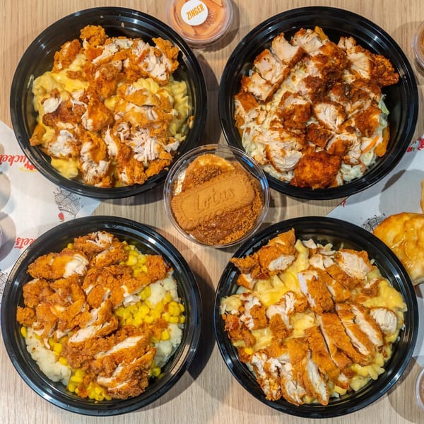 Four Holy Buckets Halal Chicken bowls with various sides, a Zinger sauce, and a Lotus dessert.