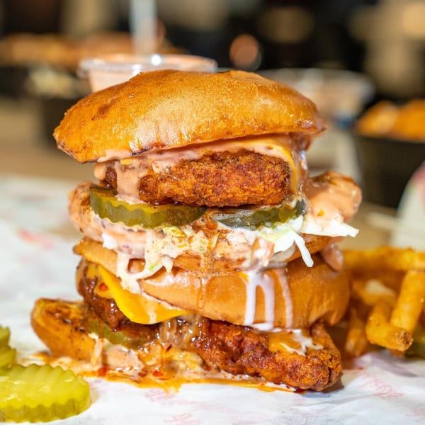 A Holy Buckets Halal Chicken & Chicken sandwich with fried chicken, pickles, coleslaw, and sauce.
